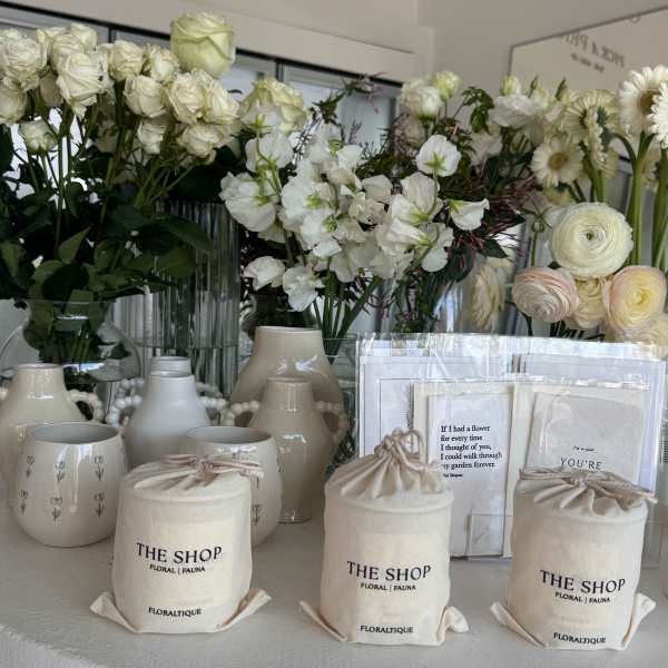 White floral arrangements with roses, ranunculus, and daisies in ceramic vases