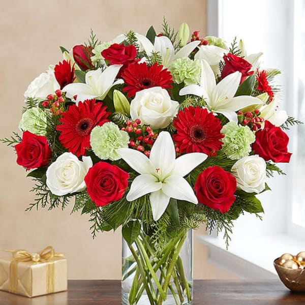 Bouquet of red roses, white lilies, and red gerbera daisies in a glass vase