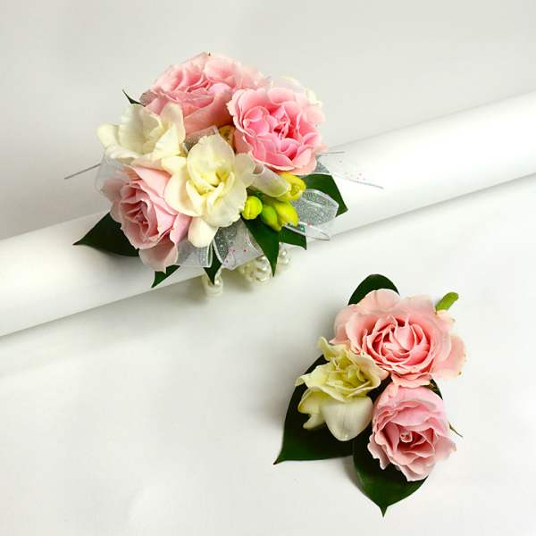 Pink and cream rose corsages with ribbon and leaves