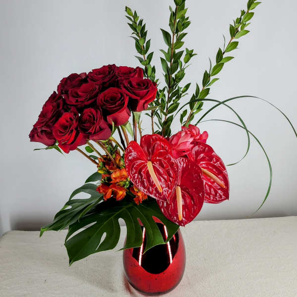 Red roses and anthuriums arranged in a red vase