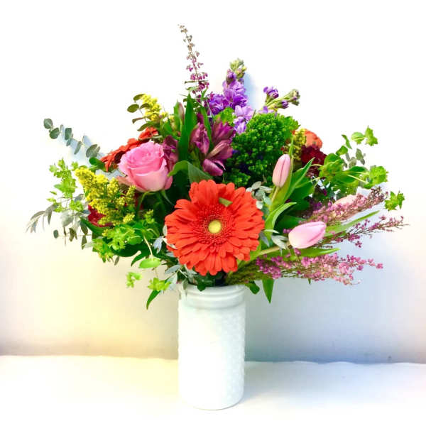 Mixed bouquet with a red gerbera daisy and pink roses in a white vase