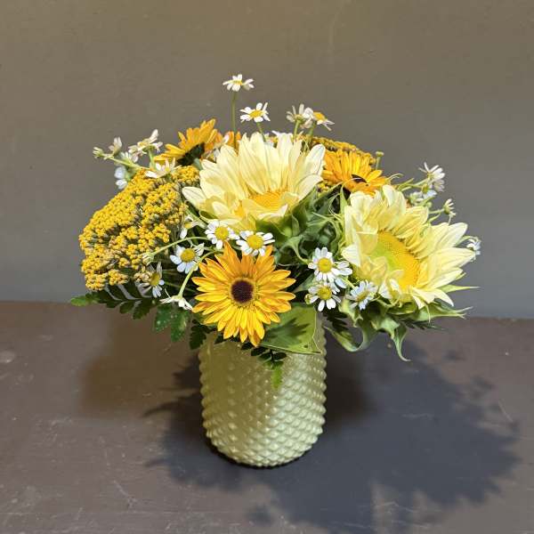 Yellow and white flowers arranged in a textured vase
