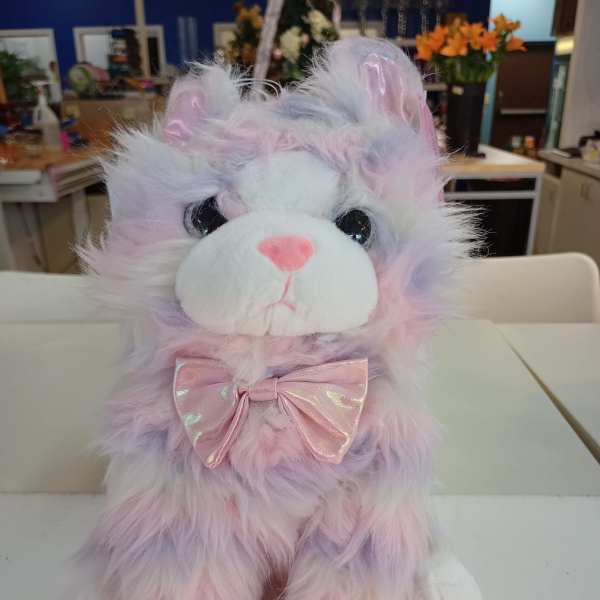 Pastel plush cat with a pink bow sitting on a table