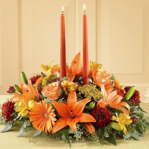 Orange floral centerpiece with two red taper candles