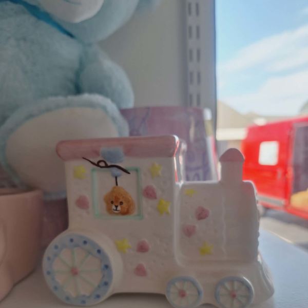 A small painted toy truck with a bear face sits on a shelf.