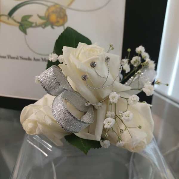 White rose corsage with silver ribbon and baby's breath