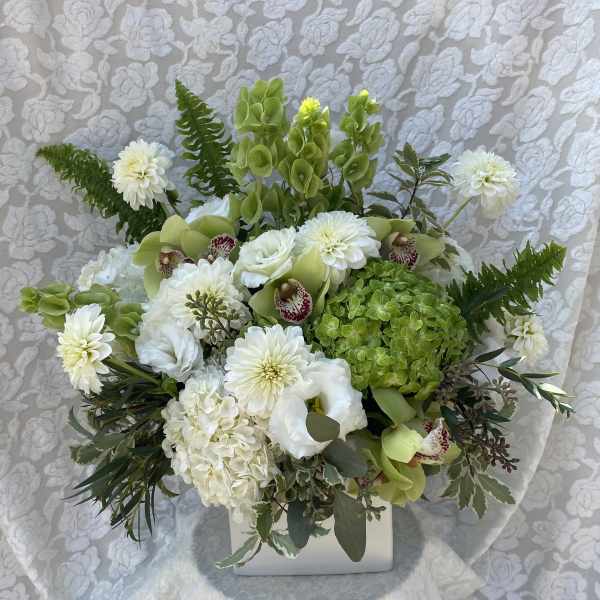 White and green floral arrangement in a white container