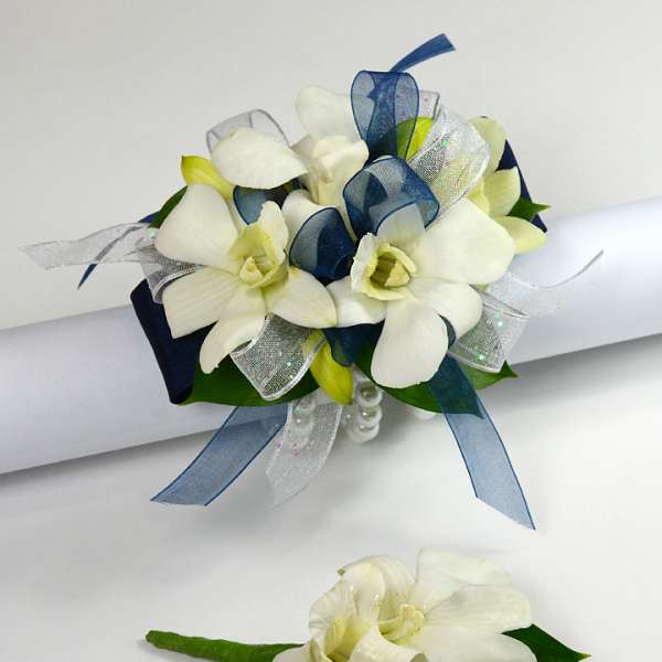 White floral wrist corsage with navy and silver ribbons and matching boutonniere.