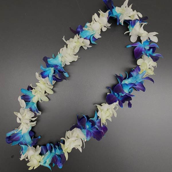 Flower lei with white, blue, and purple blossoms on a dark background