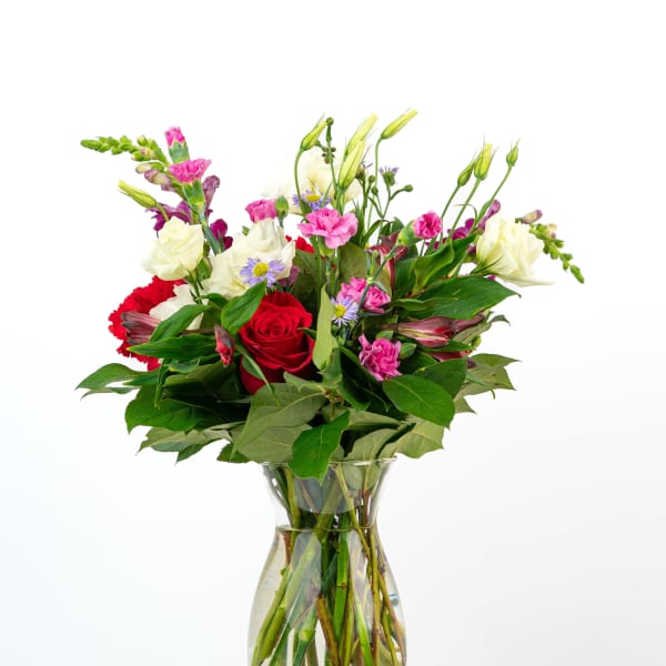 Mixed bouquet of red, pink, and white flowers in a clear glass vase