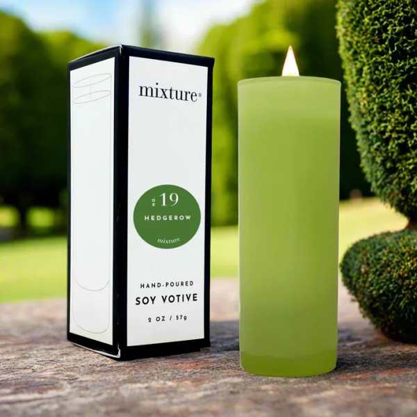 Green votive candle beside its boxed packaging