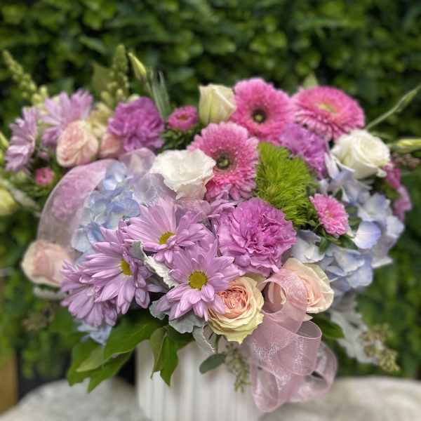 Pink and lavender bouquet with roses, daisies, and hydrangea in a white vase