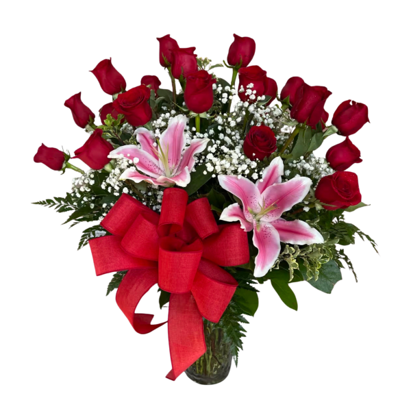 Arrangement of red roses, pink lilies, and white filler flowers in a clear glass vase with a large red bow