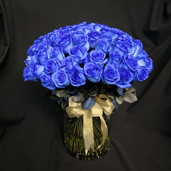 Blue rose bouquet in a glass vase with a gold ribbon