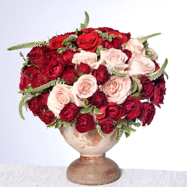 Red and blush roses arranged in a ceramic vase