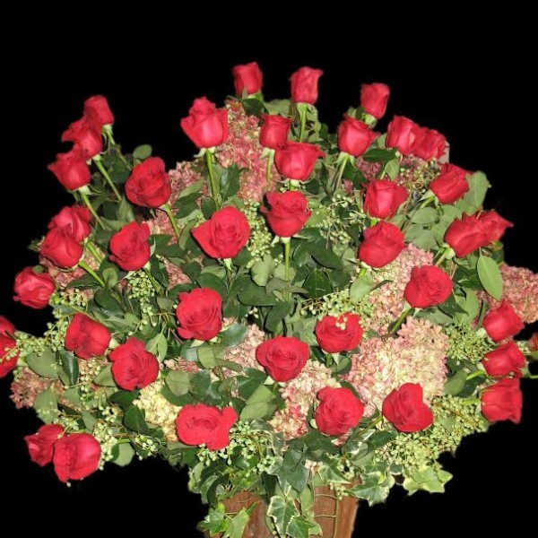 Large arrangement of red roses in a wooden container