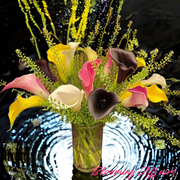Tall bouquet of multicolored calla lilies in a clear glass vase