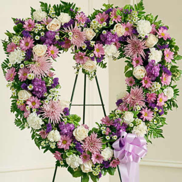 Heart-shaped floral wreath with pink, purple, and white flowers on an easel