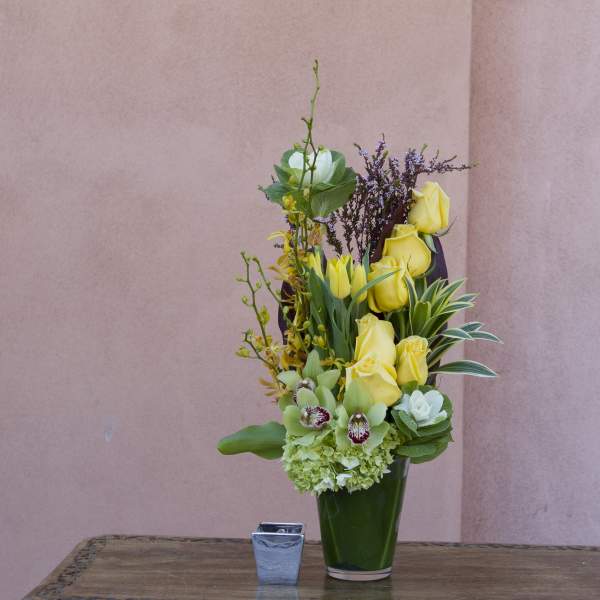 Tall yellow rose arrangement in a green vase with mixed blooms