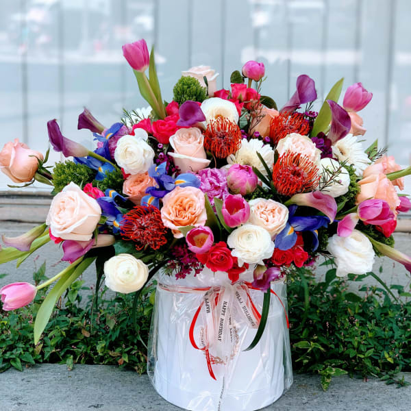 Large mixed bouquet of roses, tulips, calla lilies, and other blooms in a white hat box