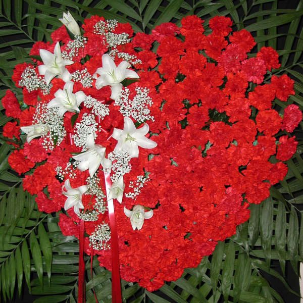 Heart-shaped red carnation spray with white lilies and ribbon