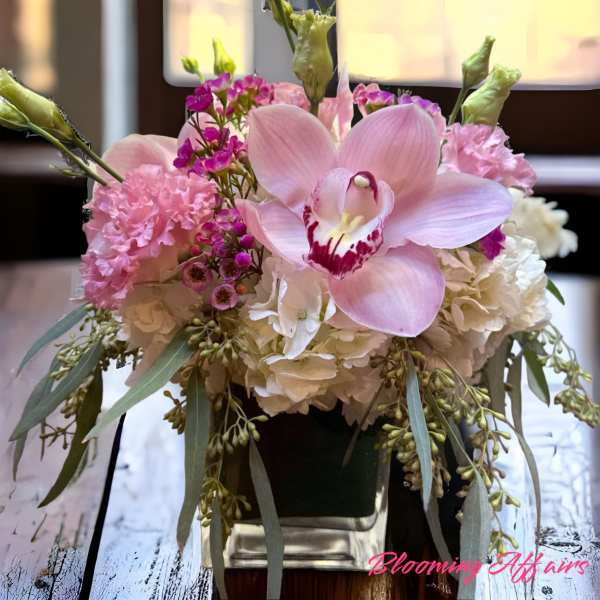 Pink orchid and hydrangea arrangement in a square vase