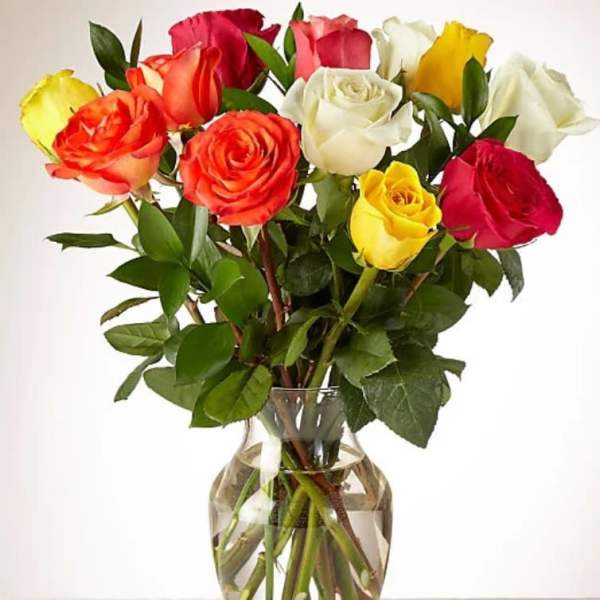 Mixed bouquet of red, yellow, white, and orange roses arranged in a clear glass vase