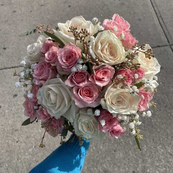 Handheld bouquet of pink and white roses with baby's breath