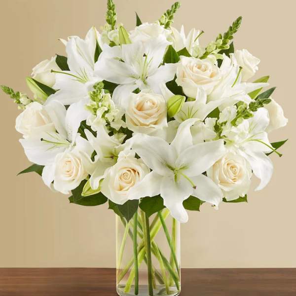White lilies and cream roses in a clear glass vase