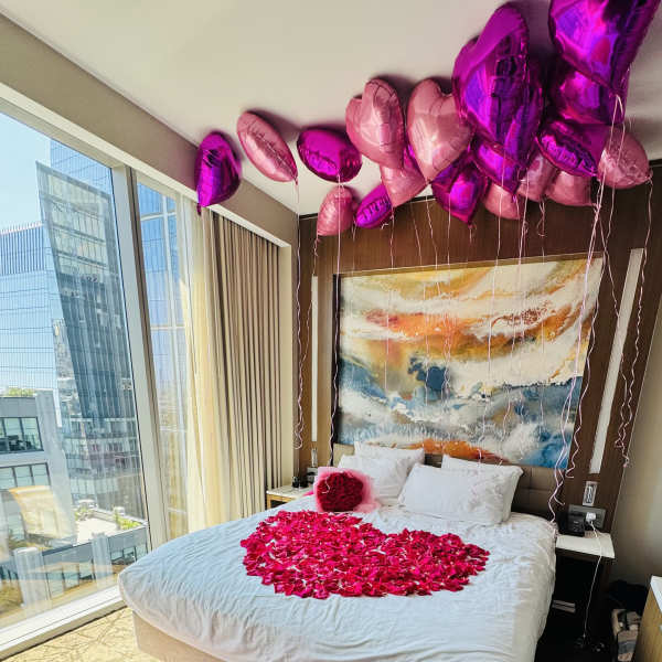 Bedroom decorated with pink heart-shaped petals and balloons