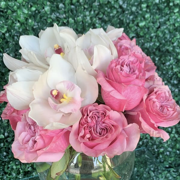 Pink roses and white orchids arranged in a glass vase