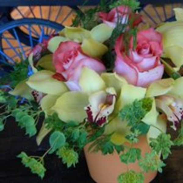 Pink roses and pale yellow orchids in a small pot