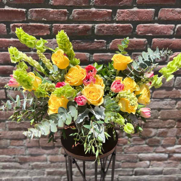 Yellow and pink rose arrangement in a dark vase