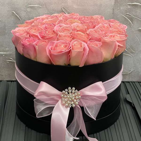 Round black hatbox filled with pink roses and tied with a pink ribbon bow