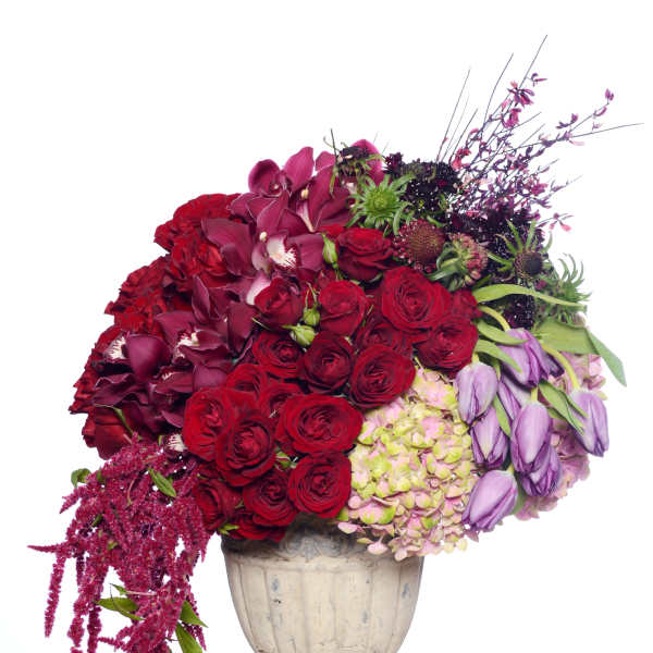 Large bouquet of red and purple flowers in a cream urn vase