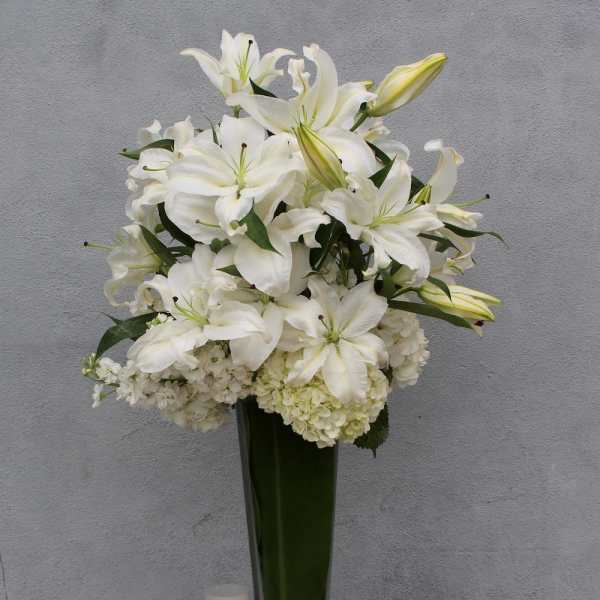 White lilies and hydrangeas arranged in a tall glass vase