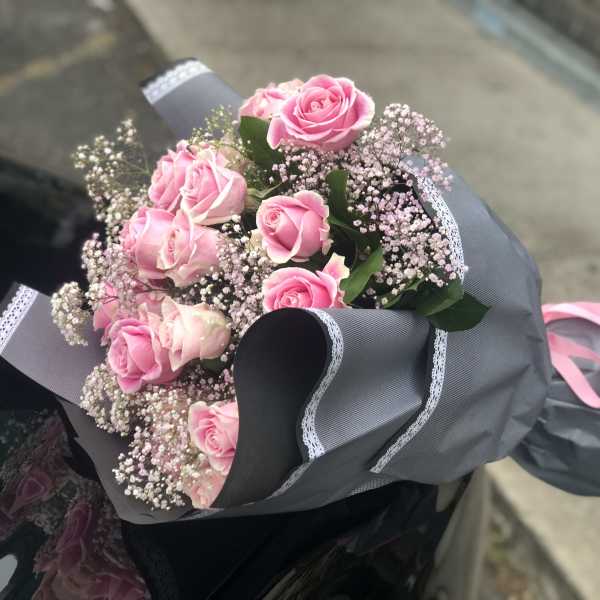 Bouquet of pink roses wrapped in gray paper with a pink ribbon