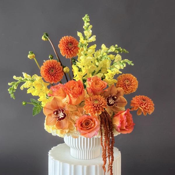 Orange and yellow floral arrangement in a white vase