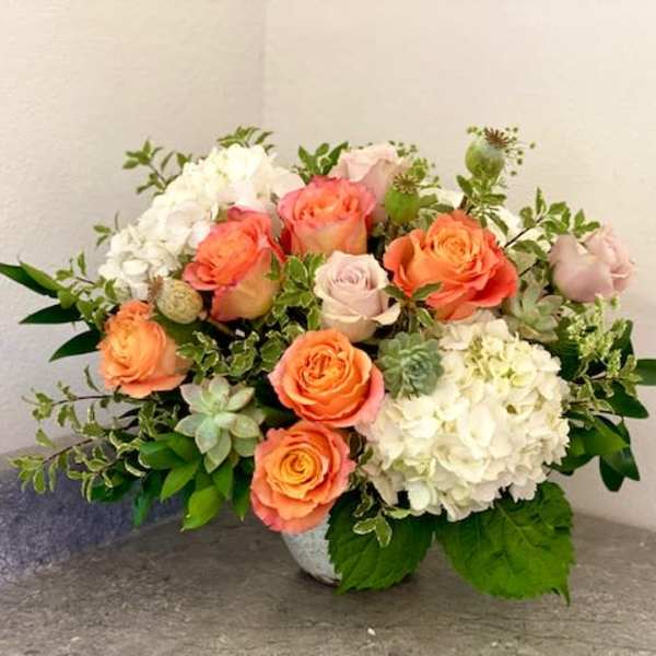 Peach roses and white hydrangeas in a low vase arrangement