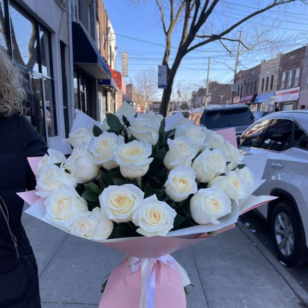 Large bouquet of white roses wrapped in pink paper with ribbon