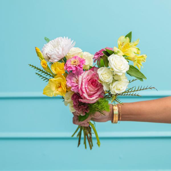 Handheld bouquet of pink, white, and yellow flowers