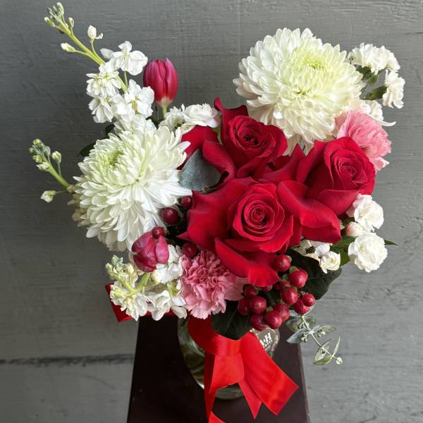 Bouquet of red roses, white chrysanthemums, and pink carnations with a red ribbon