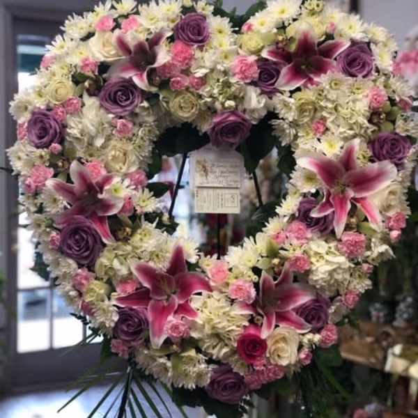Heart-shaped floral wreath with pink lilies, purple roses, and white daisies