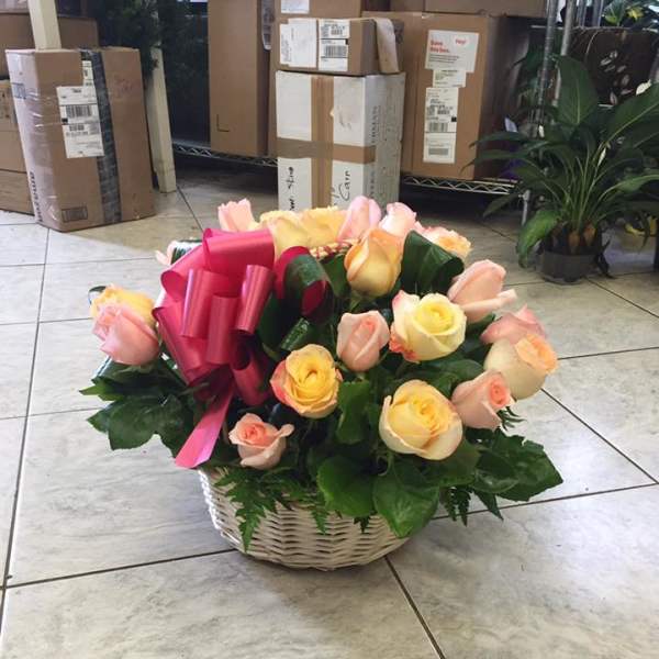 Basket of pink and yellow roses with a bright pink ribbon