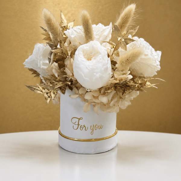 White floral arrangement in a white container with gold accents