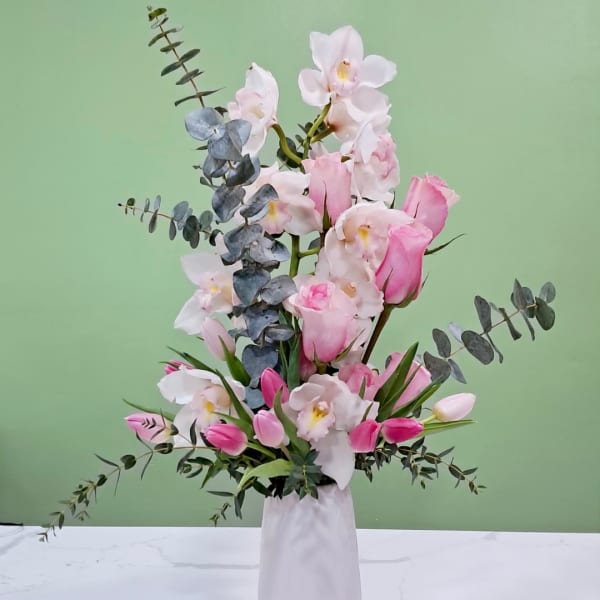 Pink and white orchid arrangement in a white vase
