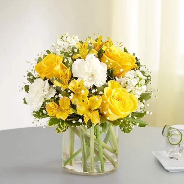Yellow and white flower bouquet in a clear glass vase