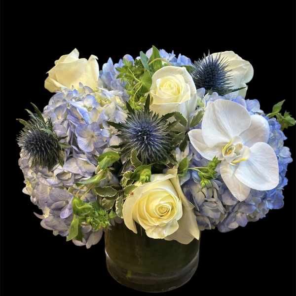 Blue hydrangeas with white roses and orchids in a glass vase