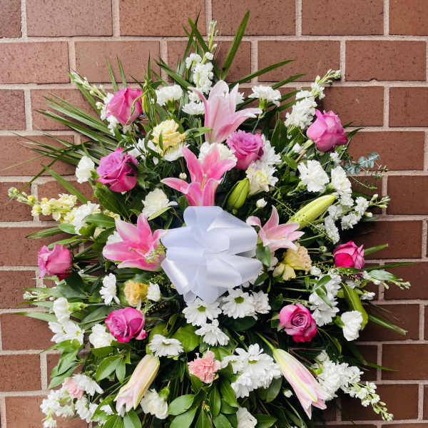 Pink and white floral standing spray with a white bow