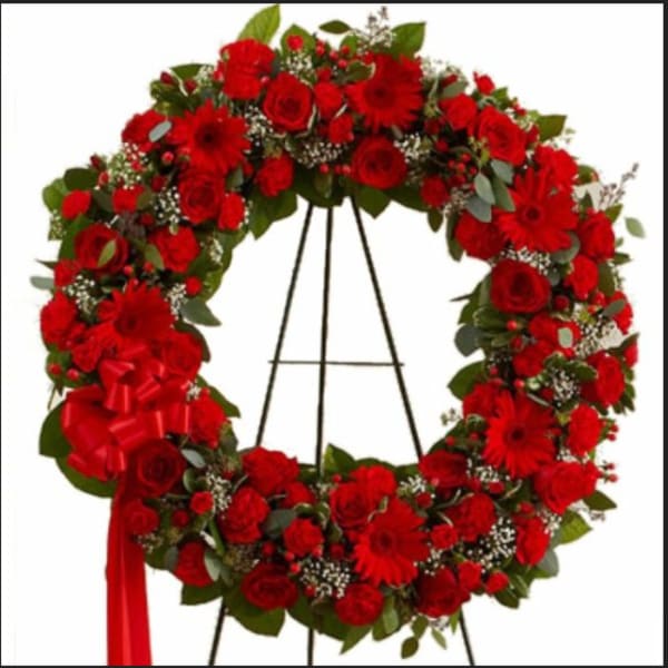 Red floral wreath on a black easel with a red ribbon